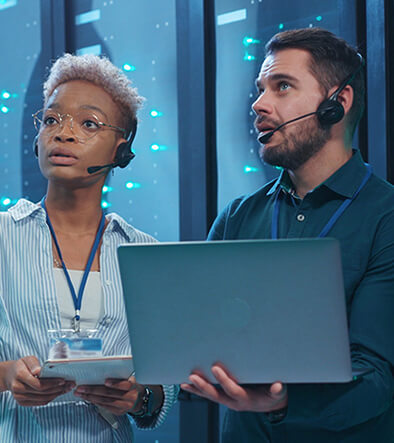 cyber security techs holding a laptop computer in server room