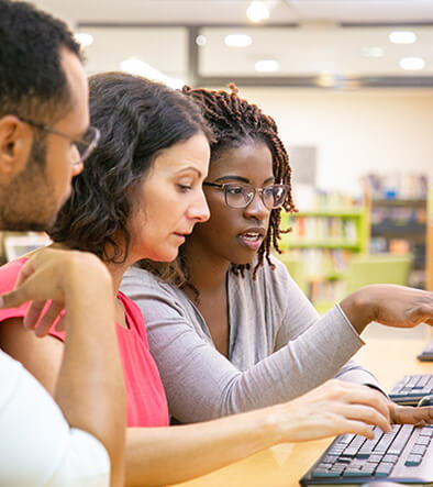 three students sitting in front of a computer in class