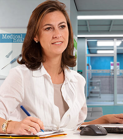 female medical administrative assistant taking notes, working on a computer
