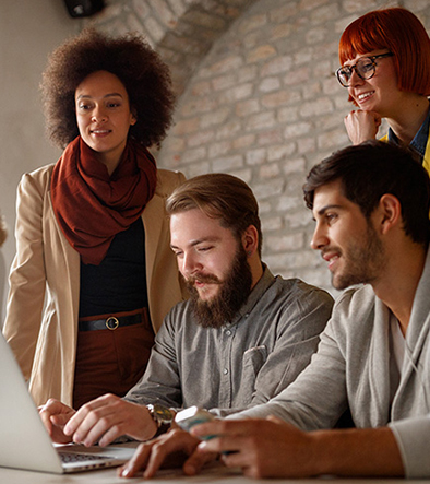 team of Web Development specialists consulting around a desk with a laptop computer